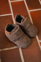 Baby Wool Camel – Babyhausschuhe aus Wolle – Bisgaard: zwei Schühchen auf einem Fliesenboden.