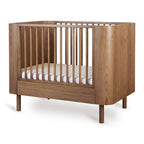 Yume Bed 110 × 70 cm – Mitwachsendes Bett aus Eschenholz – Quax: Babybett schräg von vorne.