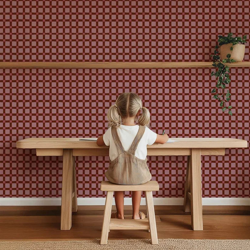 Carreaux Quilt Bordeaux – Atelier Chien : papier peint derrière un enfant à une table en bois.