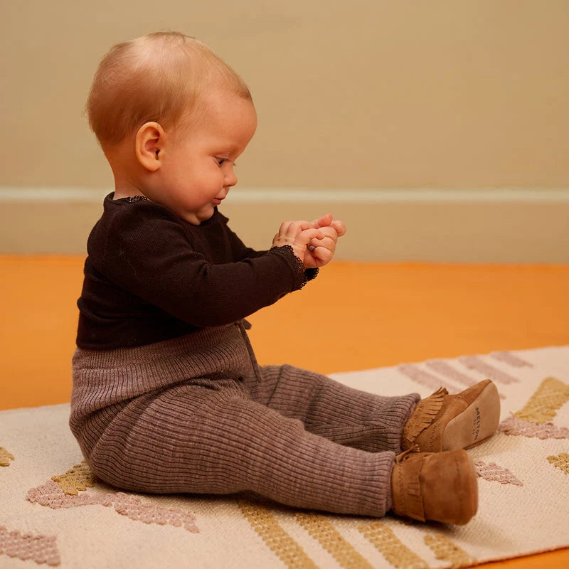 Moccasin Suede Slippers – Leren babyslofjes met suède antislipzool – MELTON: sitzendes Kind mit den Babyschuhen an.