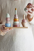 Celebrate Activity Toy – Bloomingville MINI: Detail einer Hand, die ein Teil auf einen Stapel setzt.